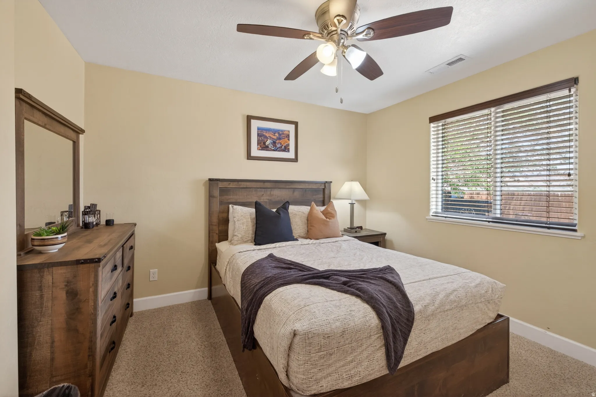 Carpeted bedroom with a window featuring blinds, a ceiling fan with integrated lighting, and neutral-toned walls