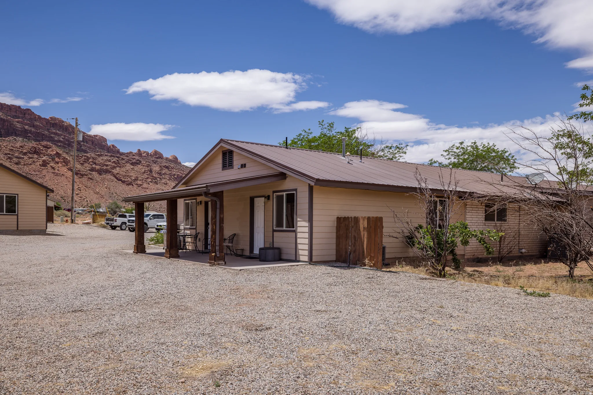 Southwest-style residence featuring a covered front porch, light-colored siding, and a brown metal roof
