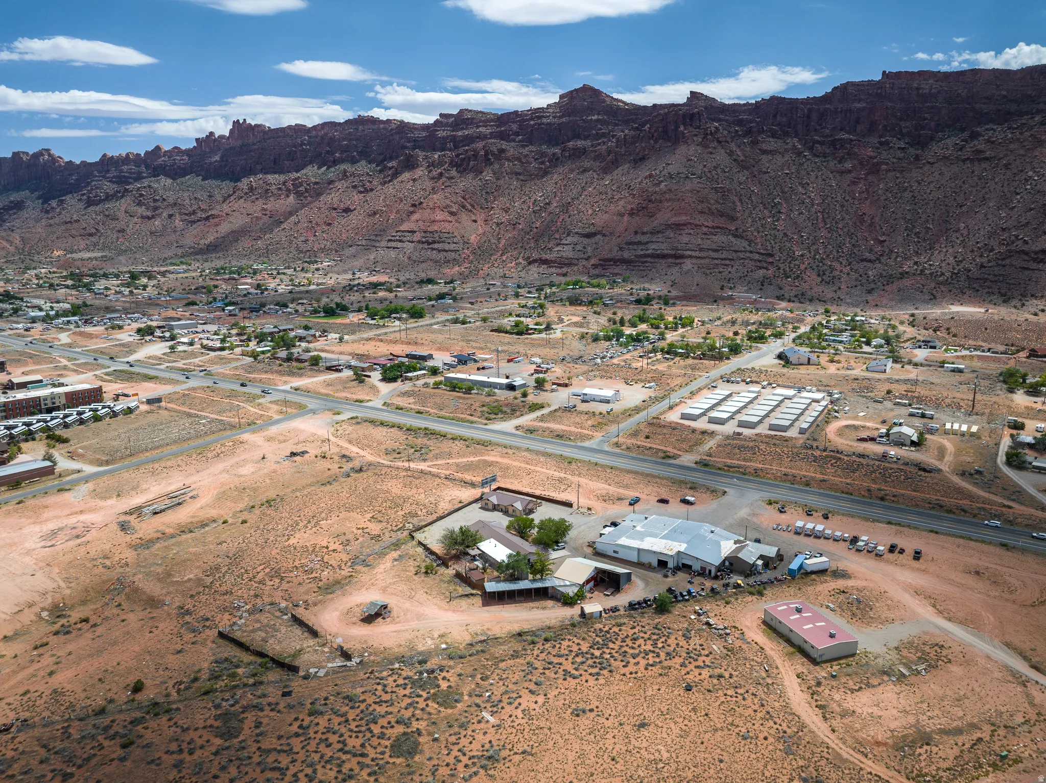 Expansive commercial property featuring multiple structures, a substantial parking area, and a large red-roofed building