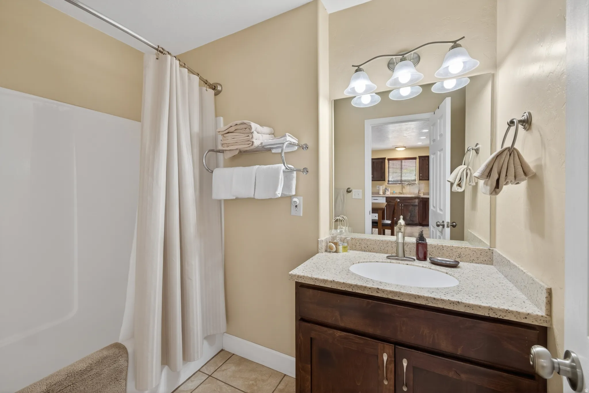 Bathroom featuring a shower-tub combination, a corner vanity with a light-toned countertop, a built-in sink, and a dark wood-finish cabinet