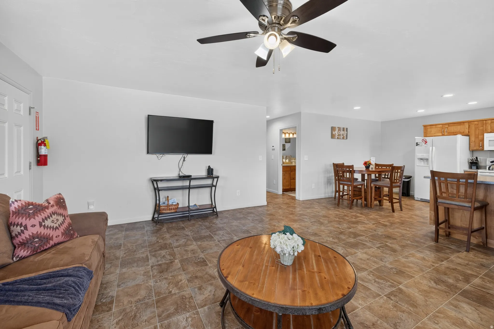 Open-concept living area featuring a ceiling fan, recessed lighting, and durable tile-finish flooring