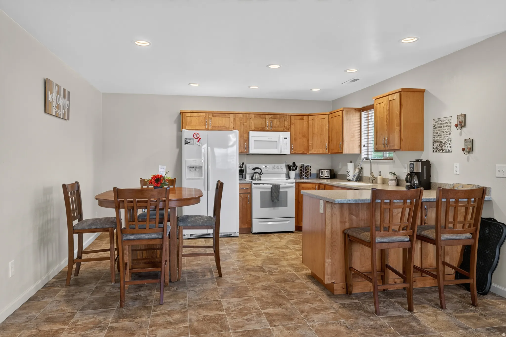 Kitchen featuring warm wood cabinetry, light countertops, and white appliances including a refrigerator and range