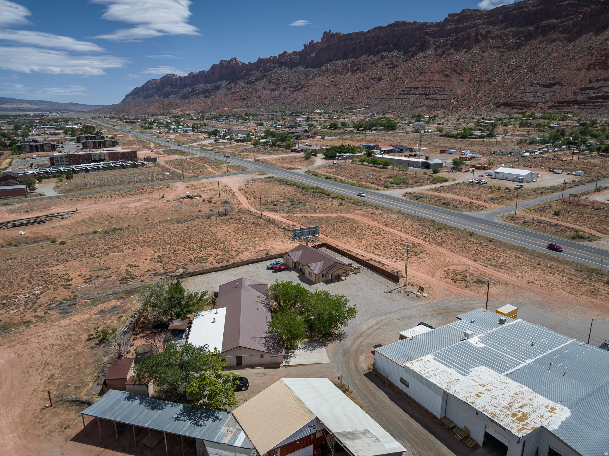 Aerial perspective showcasing multiple commercial structures with brown and white roofs, surrounded by a desert landscape