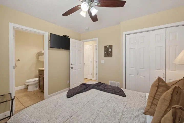 Bedroom featuring an attached bath, multi-panel closet doors, and a ceiling fan with integrated lighting