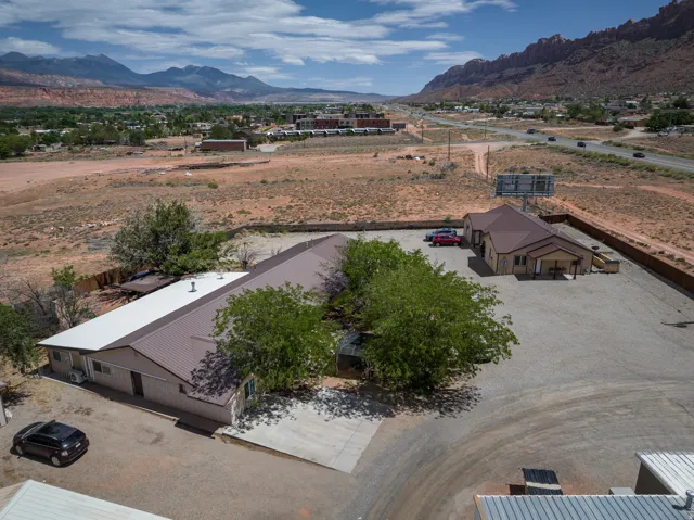 Expansive gravel lot featuring two structures with metal roofs and stucco exteriors