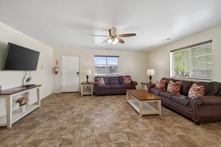 Spacious living area featuring neutral wall tones, tile flooring, and a ceiling fan