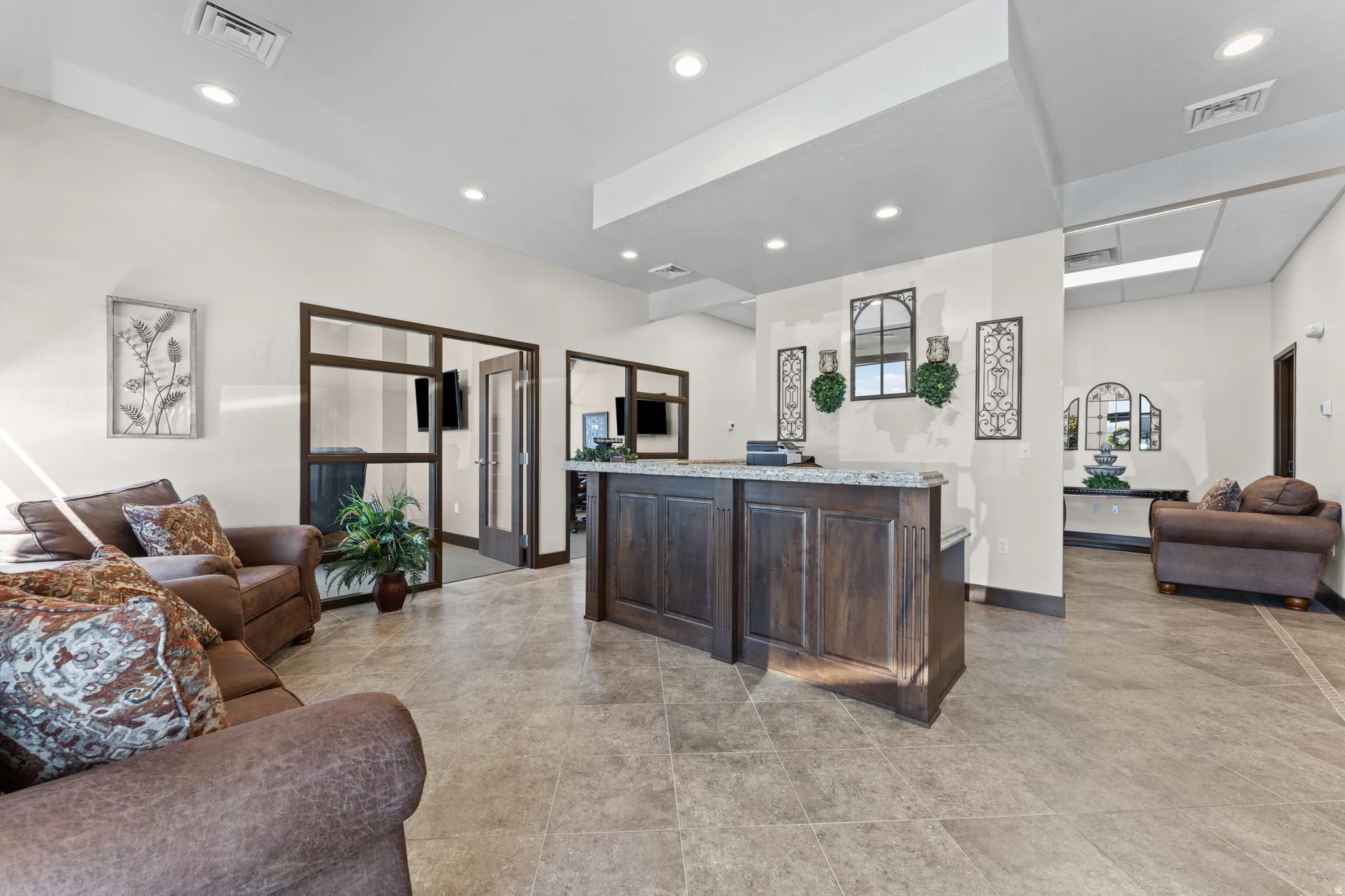 Spacious interior featuring a central built-in reception desk with a stone countertop, recessed lighting, and tile flooring