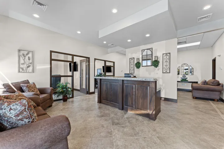 Spacious interior featuring a central built-in reception desk with a stone countertop, recessed lighting, and tile flooring