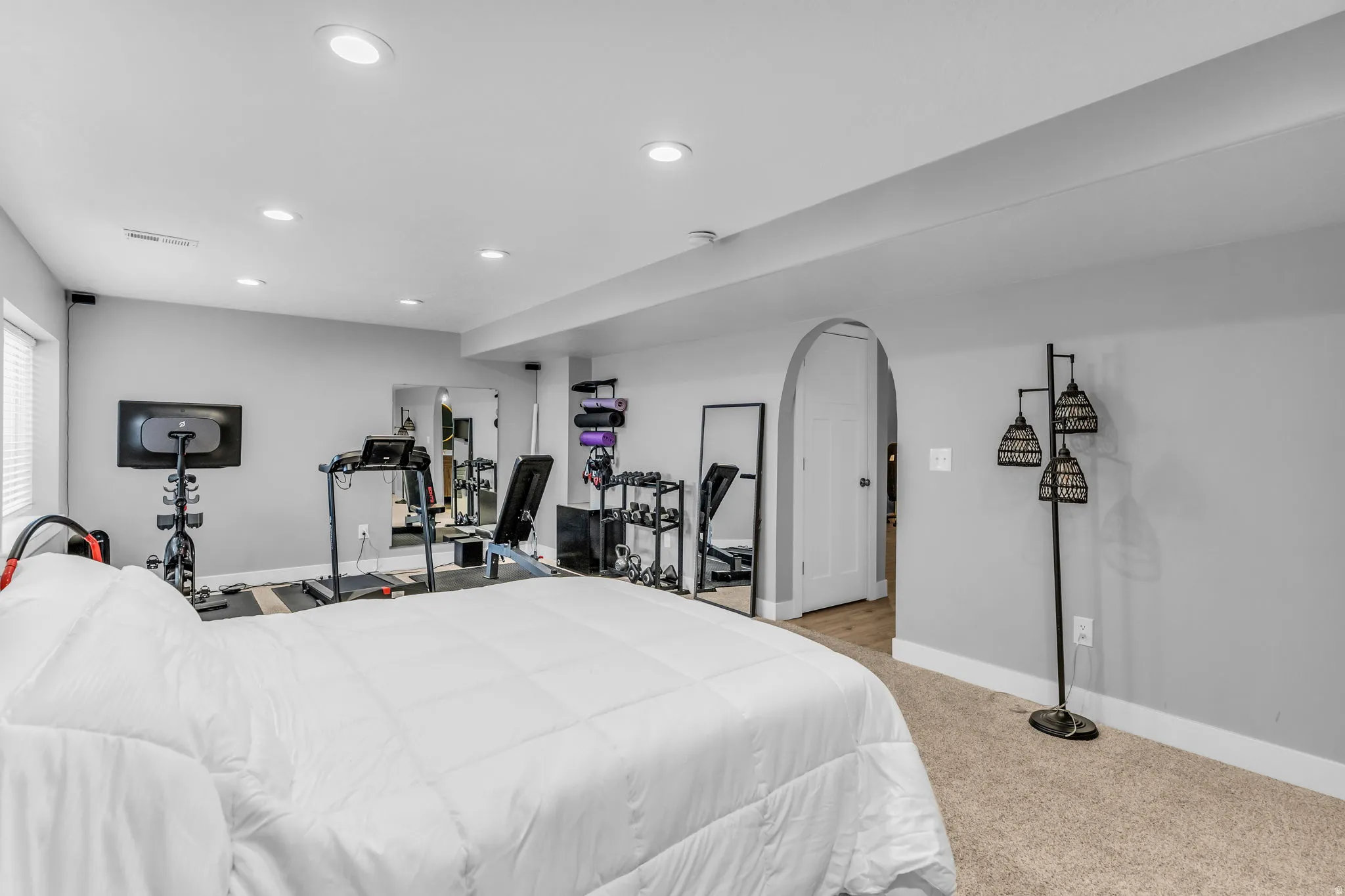 Spacious multi-purpose room featuring neutral carpeting, recessed lighting, and an arched doorway
