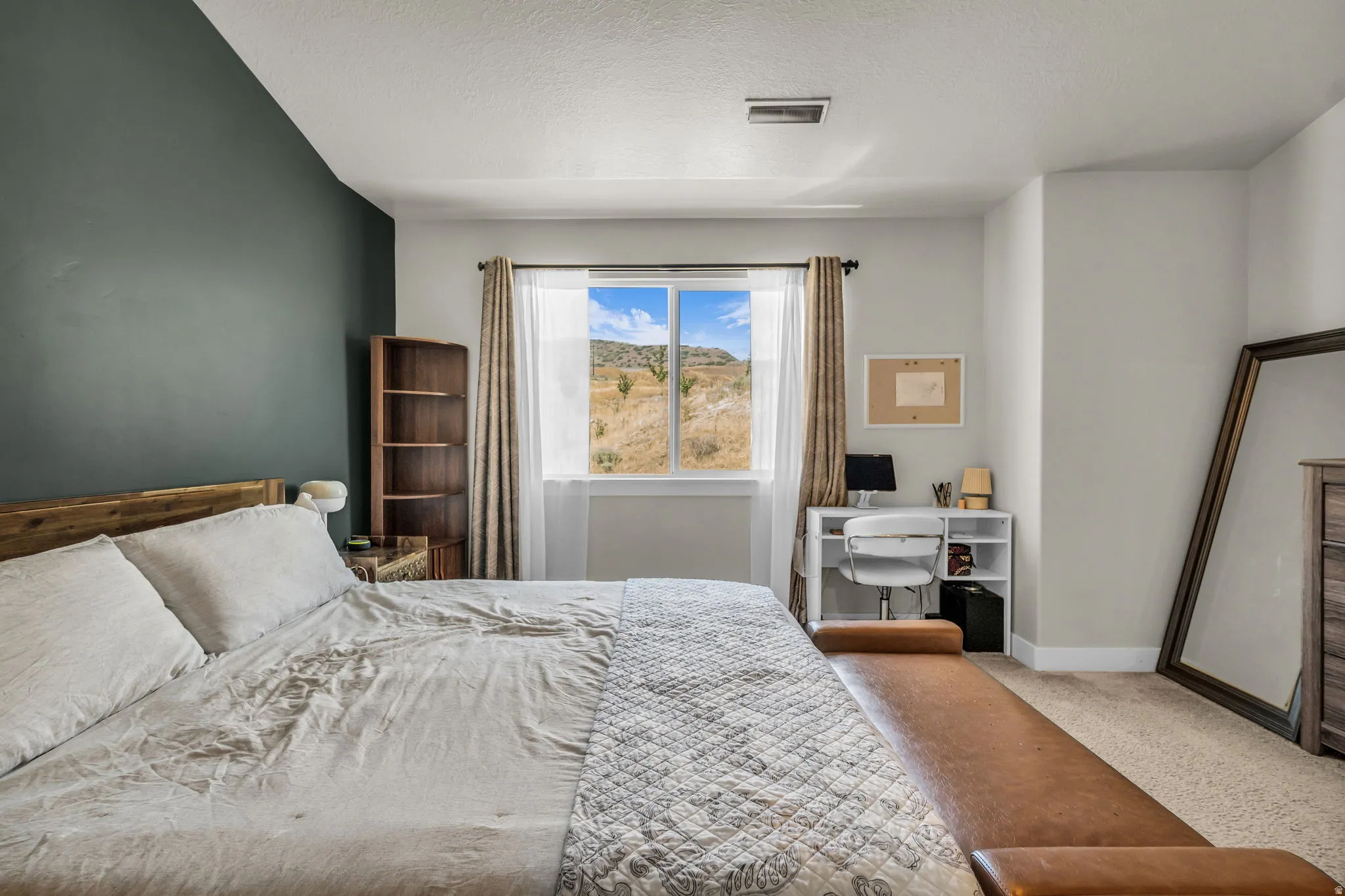 Bedroom featuring a window with natural scenery, wood-finish flooring, and built-in shelving