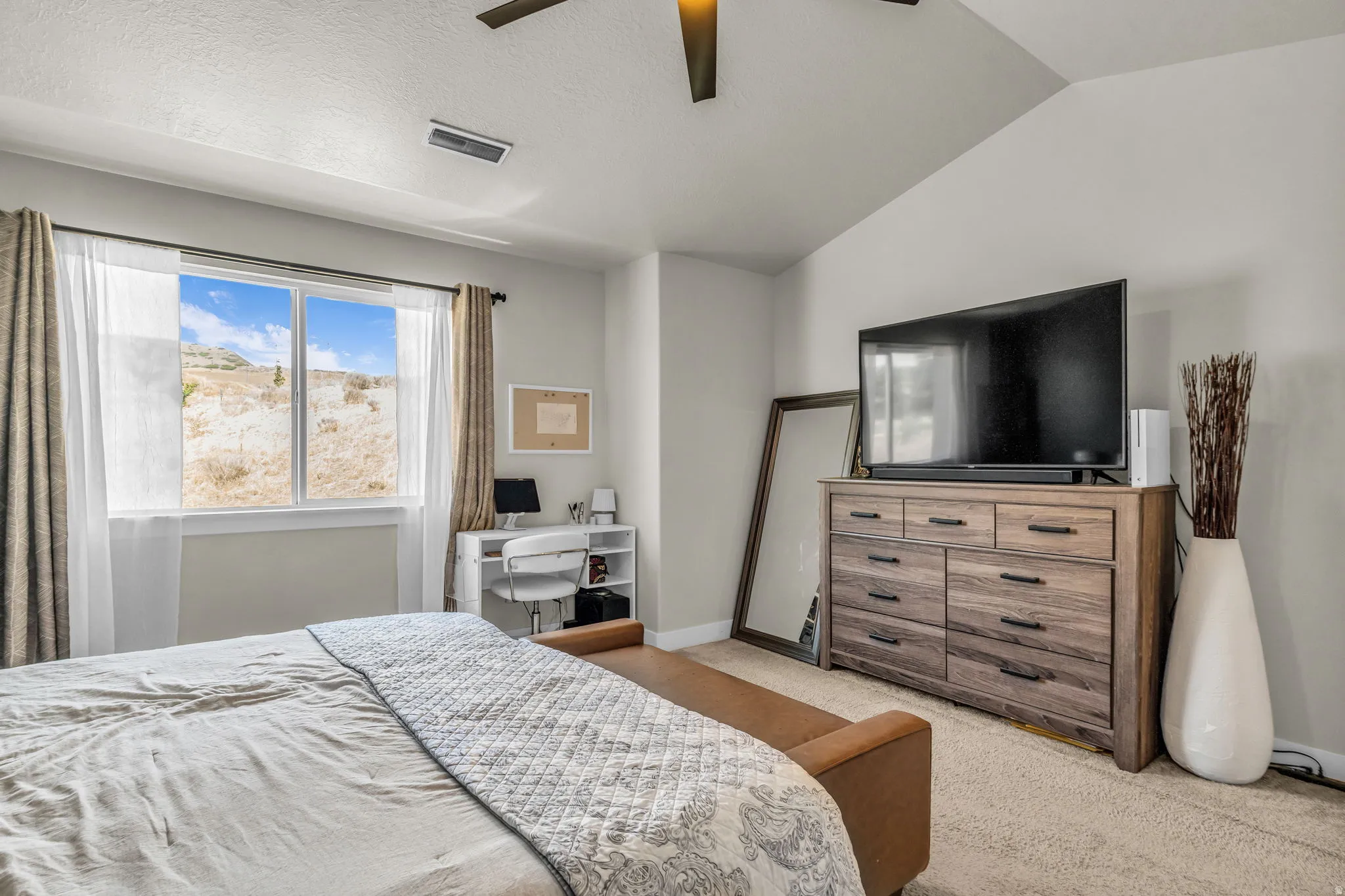 Spacious room featuring vaulted ceilings, a large window, and light-colored carpeting
