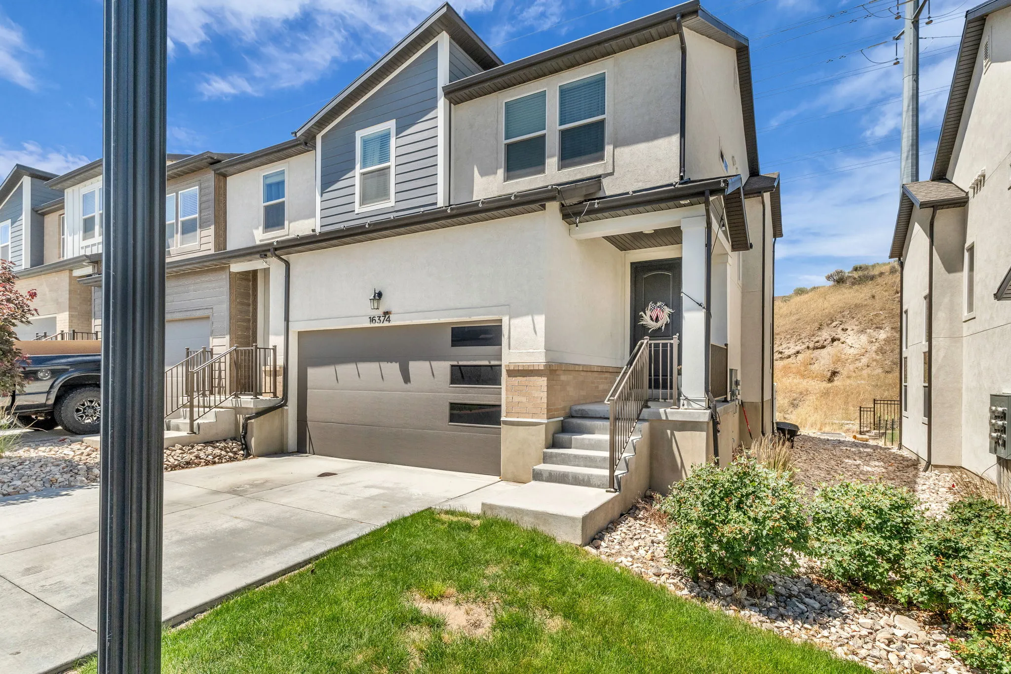 Modern townhome exterior featuring an attached garage, paved driveway, and covered entry