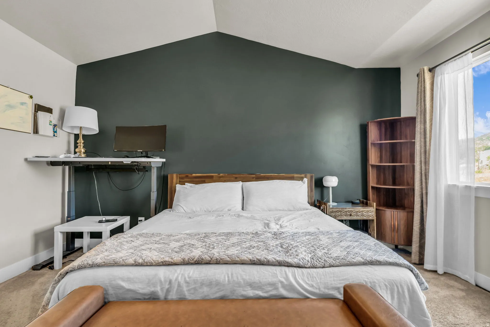 Bedroom featuring a vaulted ceiling and an accent wall