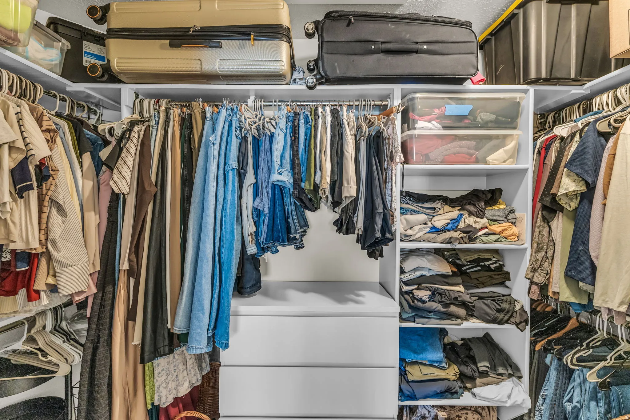 Built-in closet system featuring multiple hanging rods, open shelving, and integrated drawers