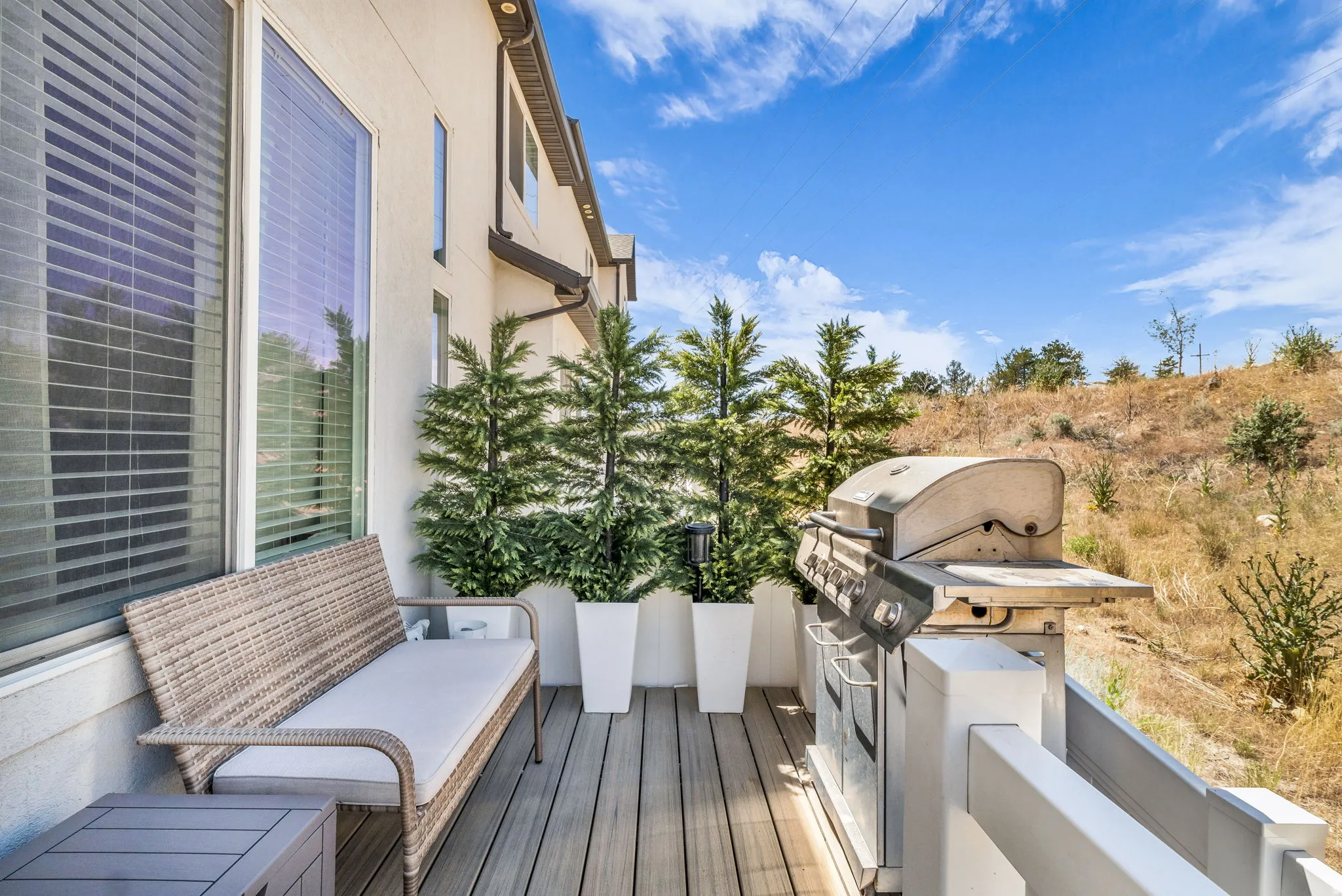 Outdoor deck featuring wood-finish composite decking, modern white railing, and a clear sky backdrop