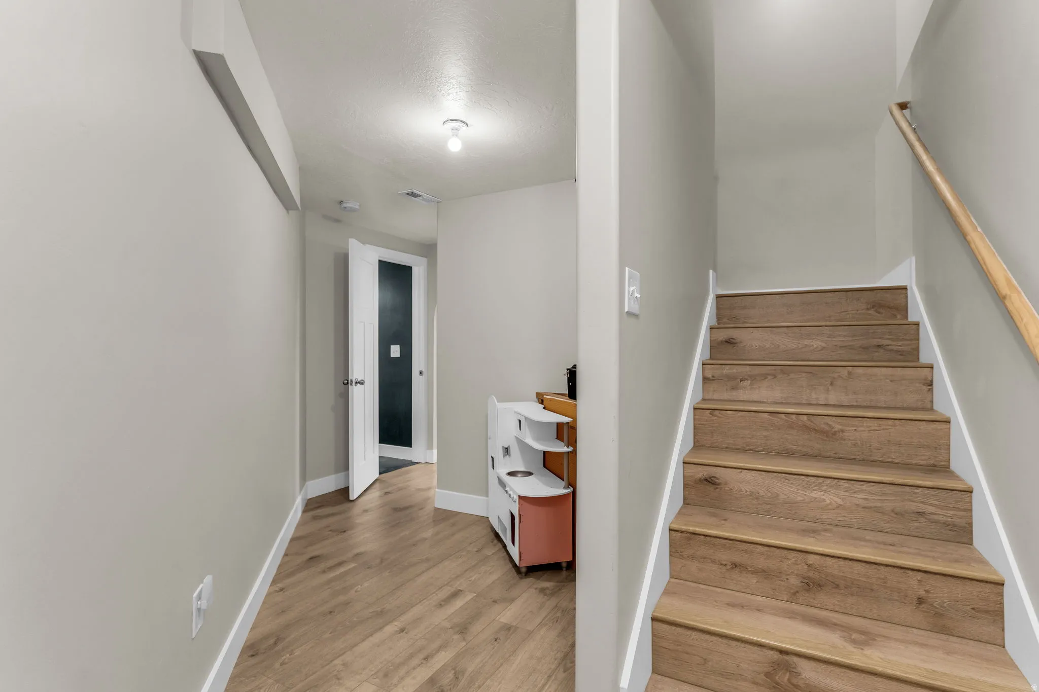 Staircase with wood-finish treads and risers, complemented by a natural wood handrail