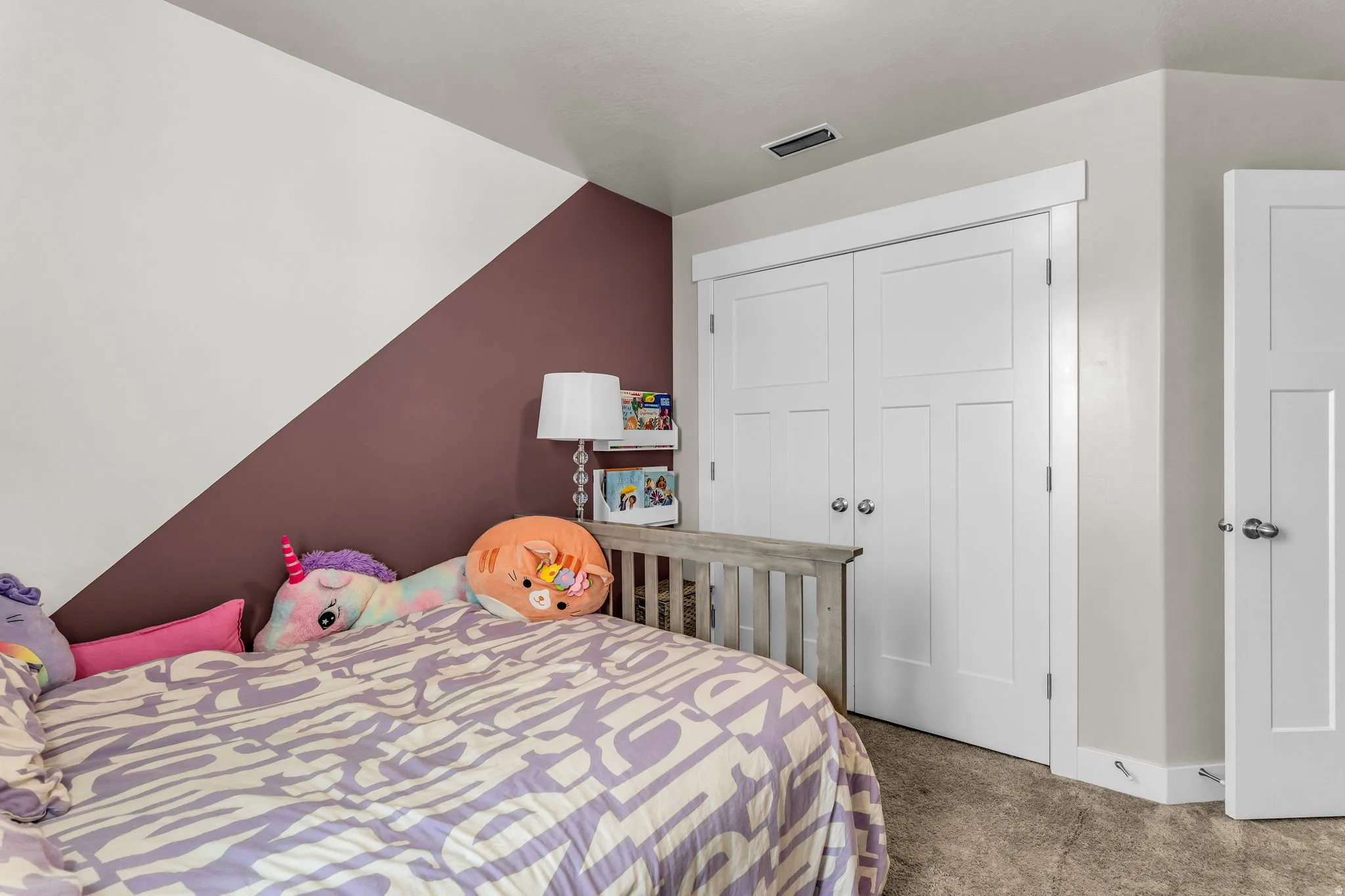 Bedroom featuring an accent wall with a unique diagonal paint line, white trim, and a white paneled closet door
