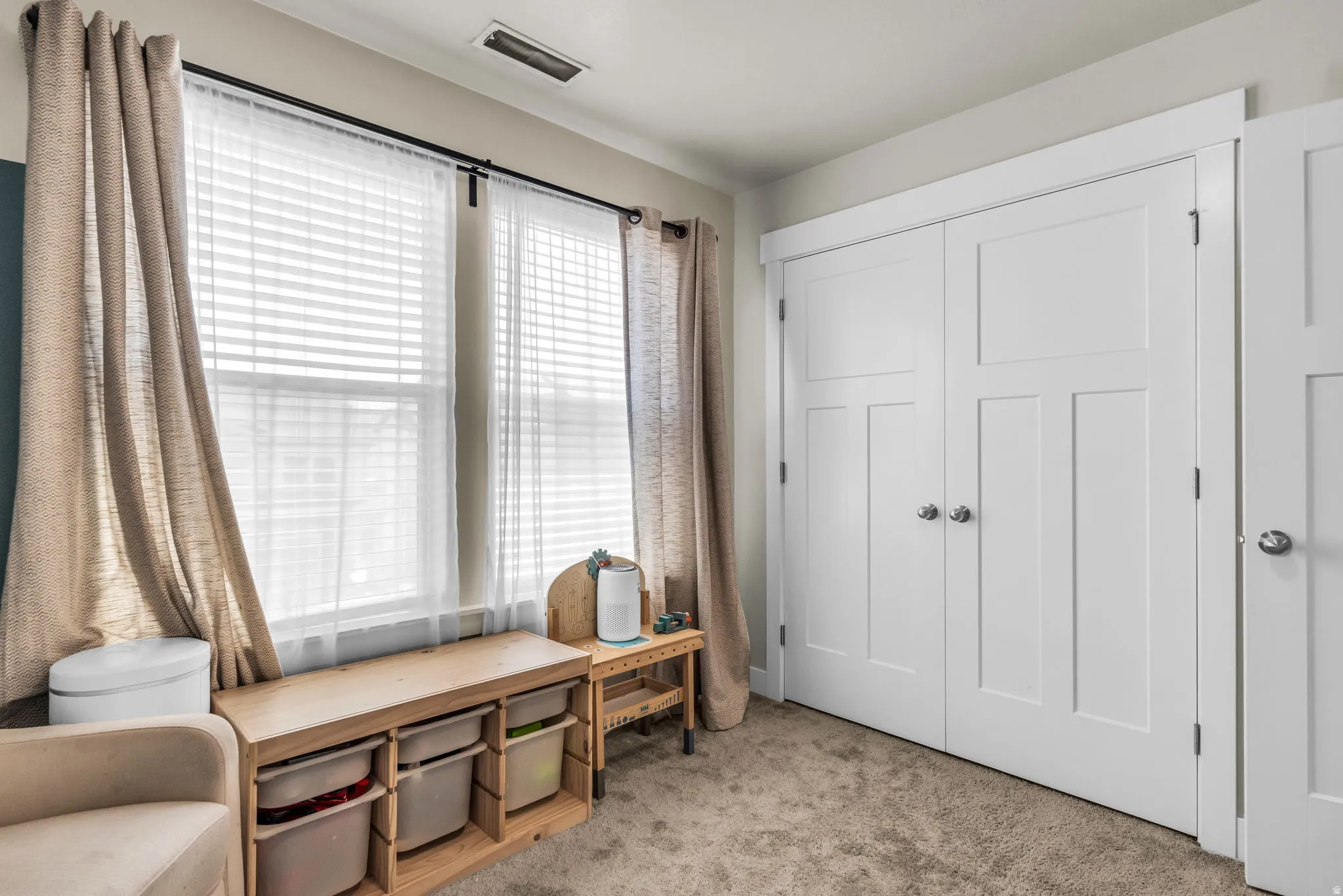 Double windows with white blinds, light-colored curtains, and a black curtain rod