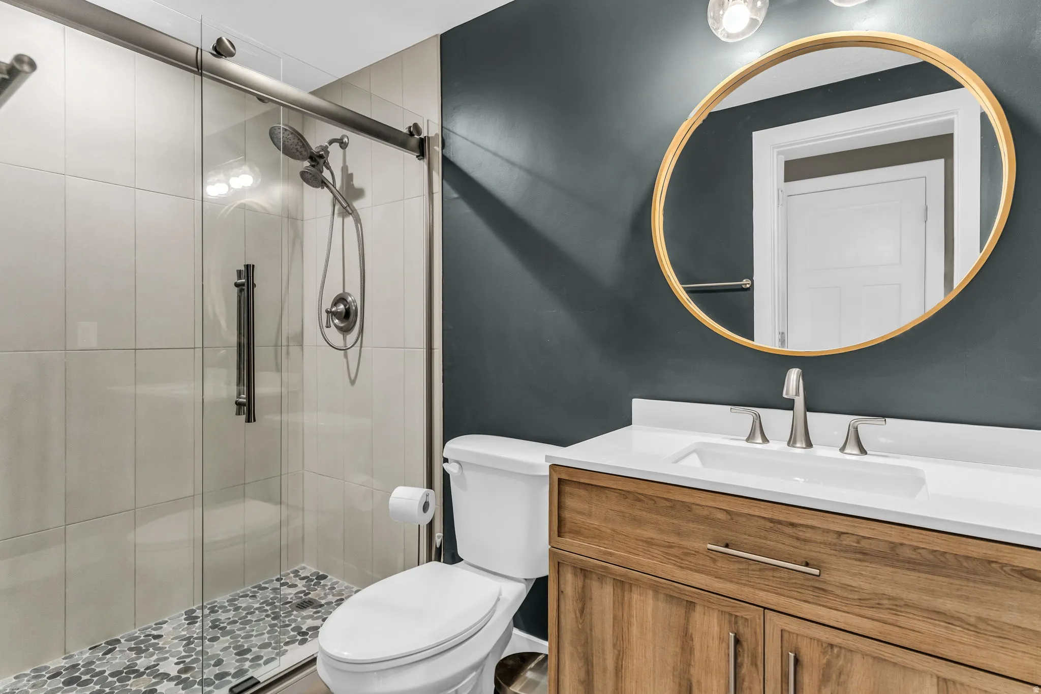 Bathroom featuring a glass-enclosed shower with tiled walls and pebble-finish floor