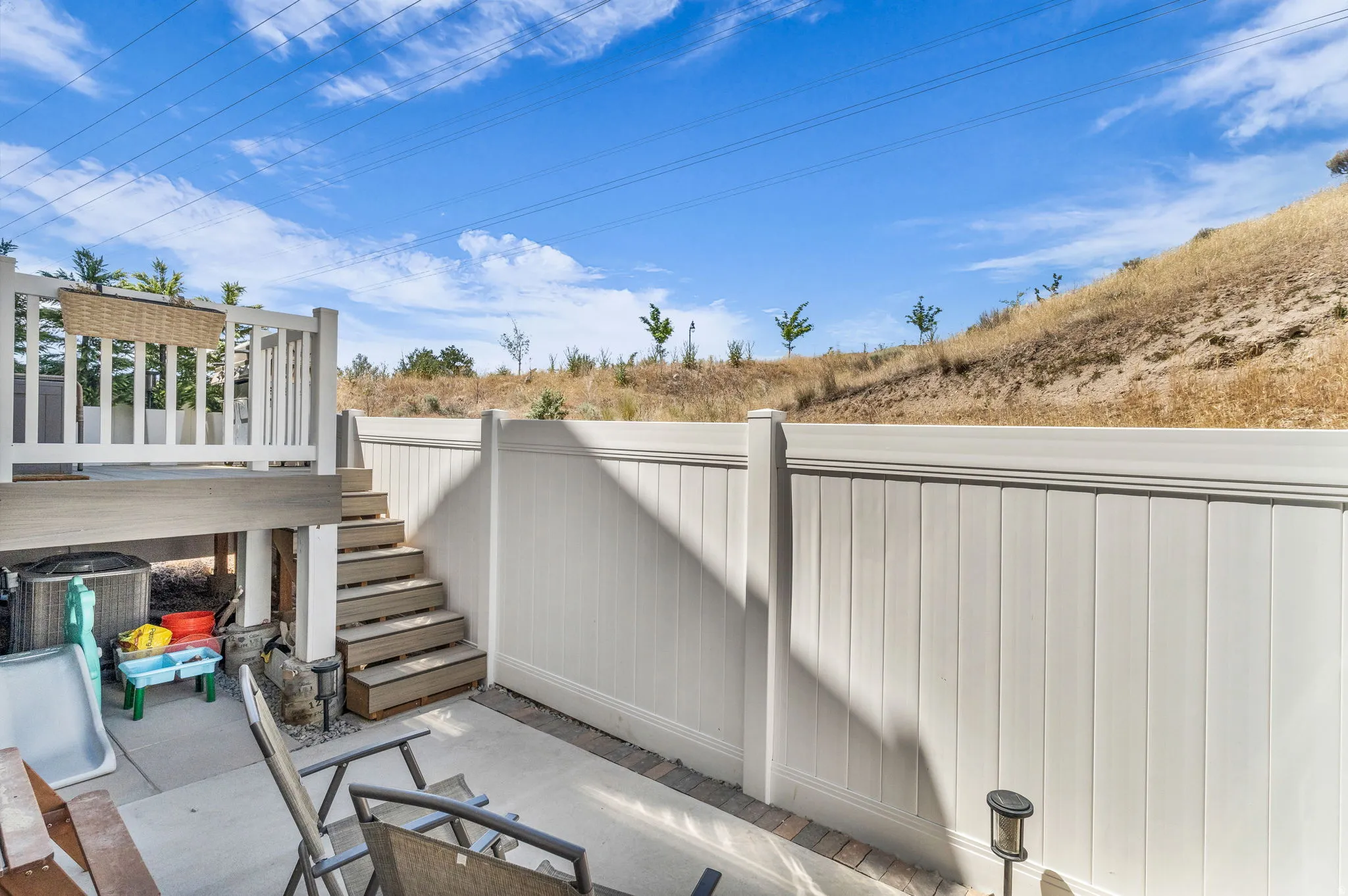 Outdoor patio area featuring a white privacy fence, multi-level composite decking, and a concrete patio