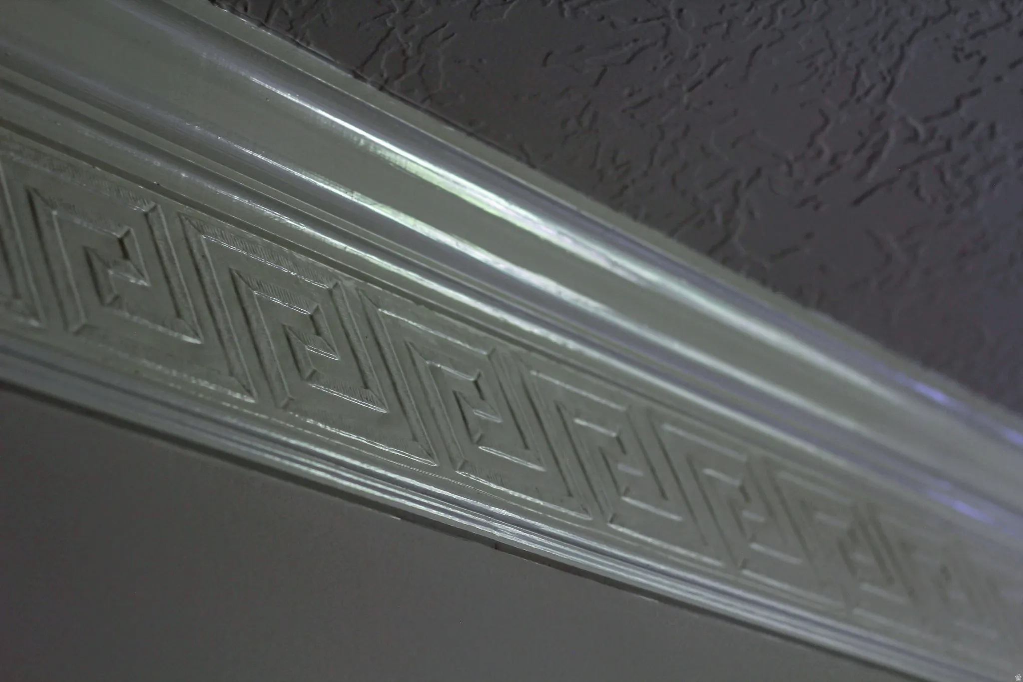 Crown molding with a Greek Key pattern, featuring a textured ceiling finish