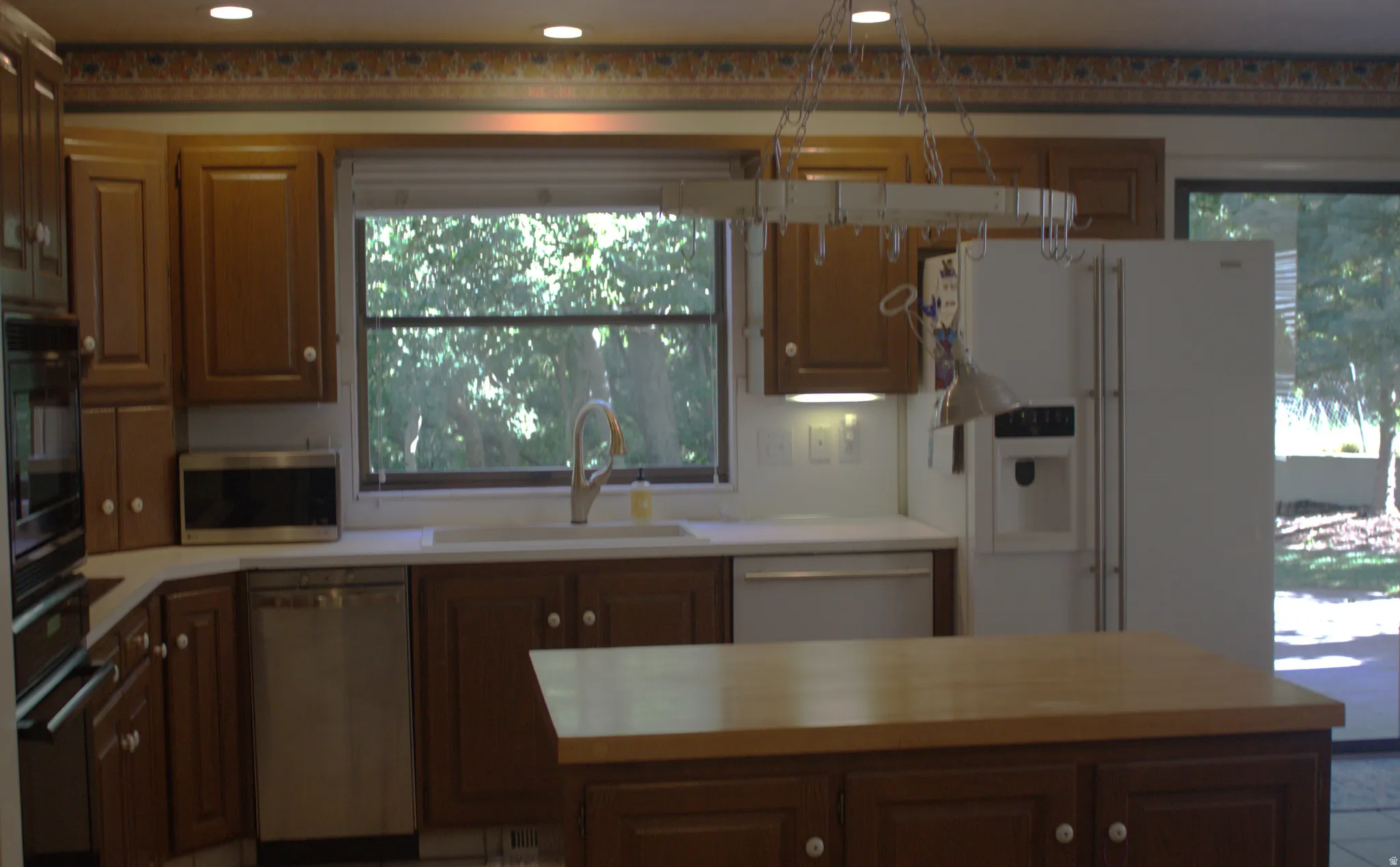 Kitchen featuring wood cabinetry, white countertops, a stainless steel dishwasher, and a built-in double oven