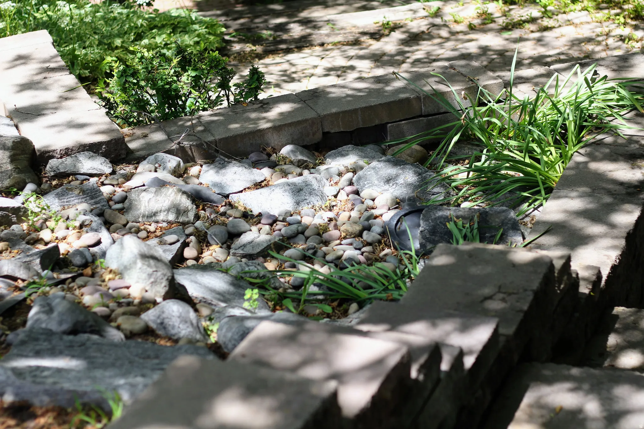 Tiered garden bed featuring a mix of natural stones and pebbles, complemented by green plantings