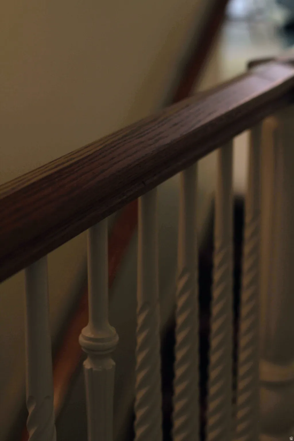 Wood-finish handrail with white painted balusters, some featuring a twisted design