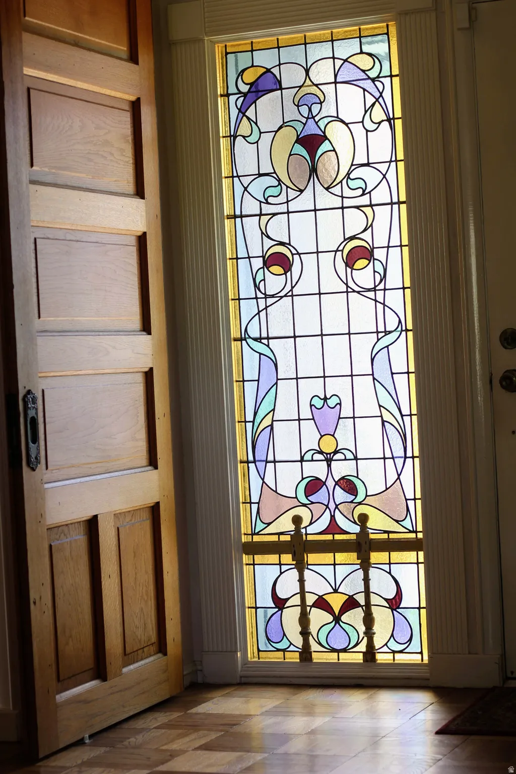 Ornate stained-glass sidelight with decorative metal grillwork