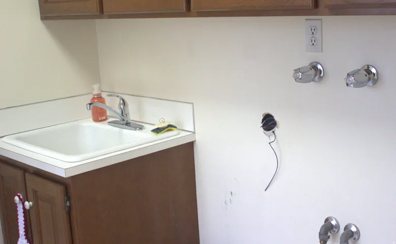 Utility sink with chrome faucet and white laminate countertop, accompanied by wood-finish cabinetry