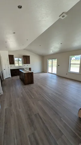 Spacious room featuring wood-finish flooring, vaulted ceilings, and recessed lighting