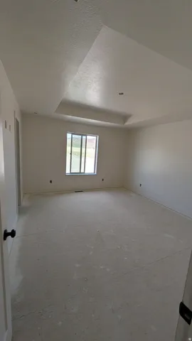 Spacious room featuring a tray ceiling, recessed lighting, and a double-pane window