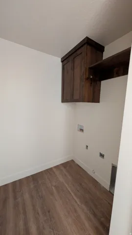 Dedicated laundry area featuring wood-finish flooring, white walls, and white baseboards