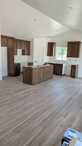 Spacious kitchen featuring extensive wood cabinetry, a central island, recessed lighting, wood-finish flooring, and a large window