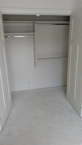 Closet with double bi-fold panel doors, interior shelving, and chrome hanging rods