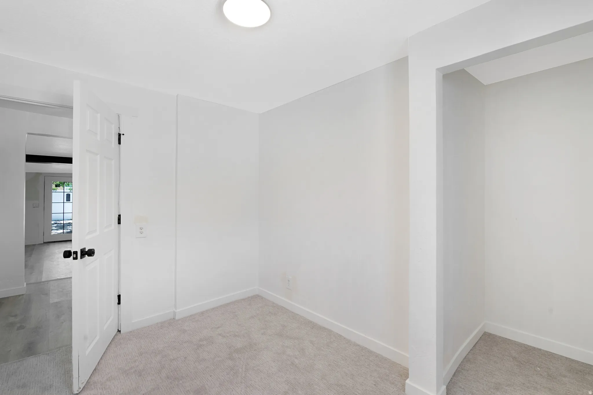 Carpeted interior room featuring white walls and trim