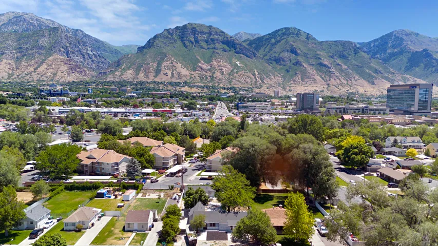 Expansive mountain backdrop with a vibrant urban landscape featuring diverse architectural styles and mature trees