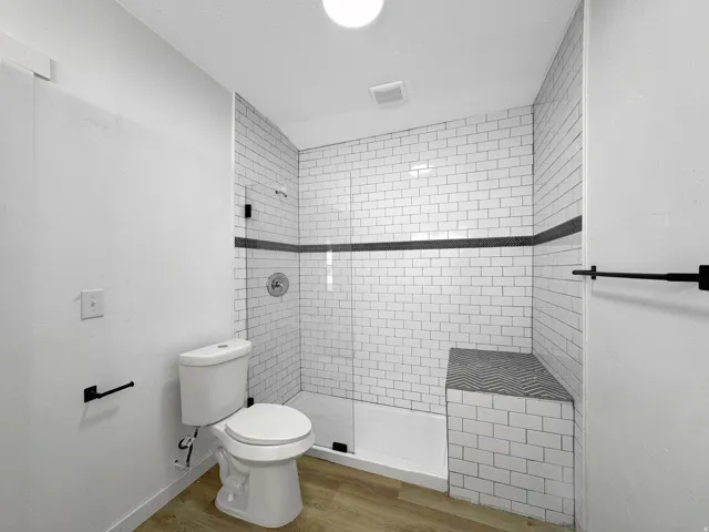 Shower enclosure featuring subway tile surround with a decorative accent band and integrated bench seating