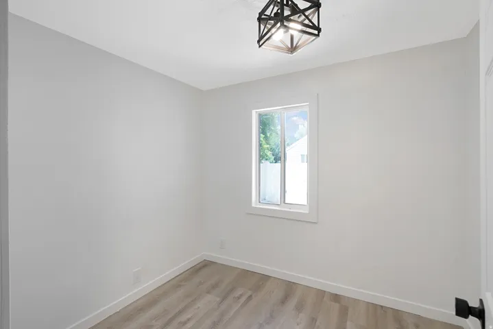 Interior room featuring a single window, overhead semi-flush mount lighting, light wood-finish flooring, white baseboards, and neutral wall paint