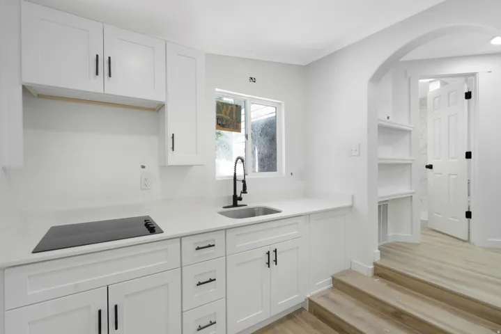 Additional kitchen. Contemporary white kitchen with quartz countertops, integrated cooktop, undermount sink, and matte black fixtures