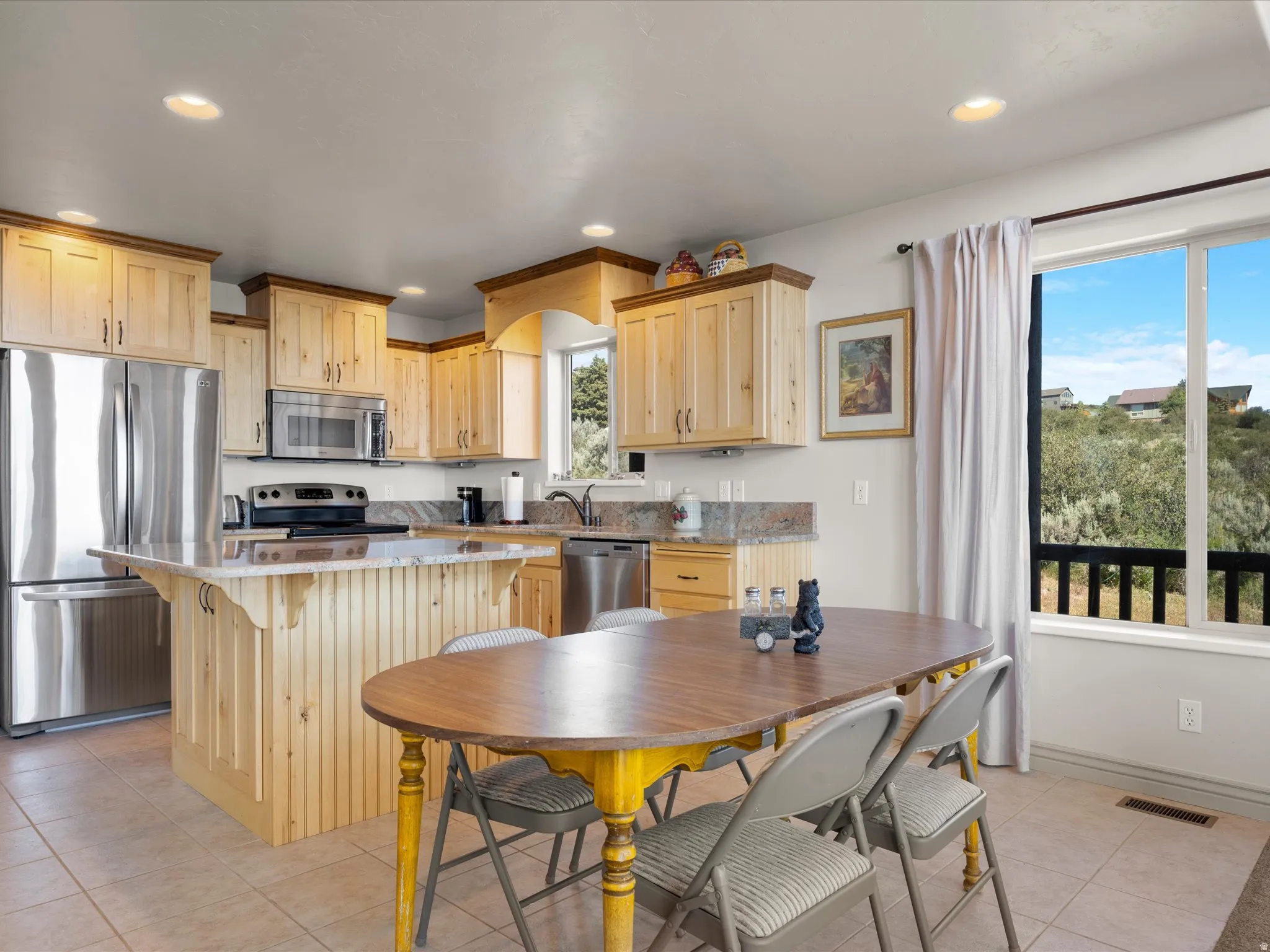 Kitchen featuring light wood cabinetry with dark crown molding, stainless steel appliances, stone-finish countertops, and recessed lighting