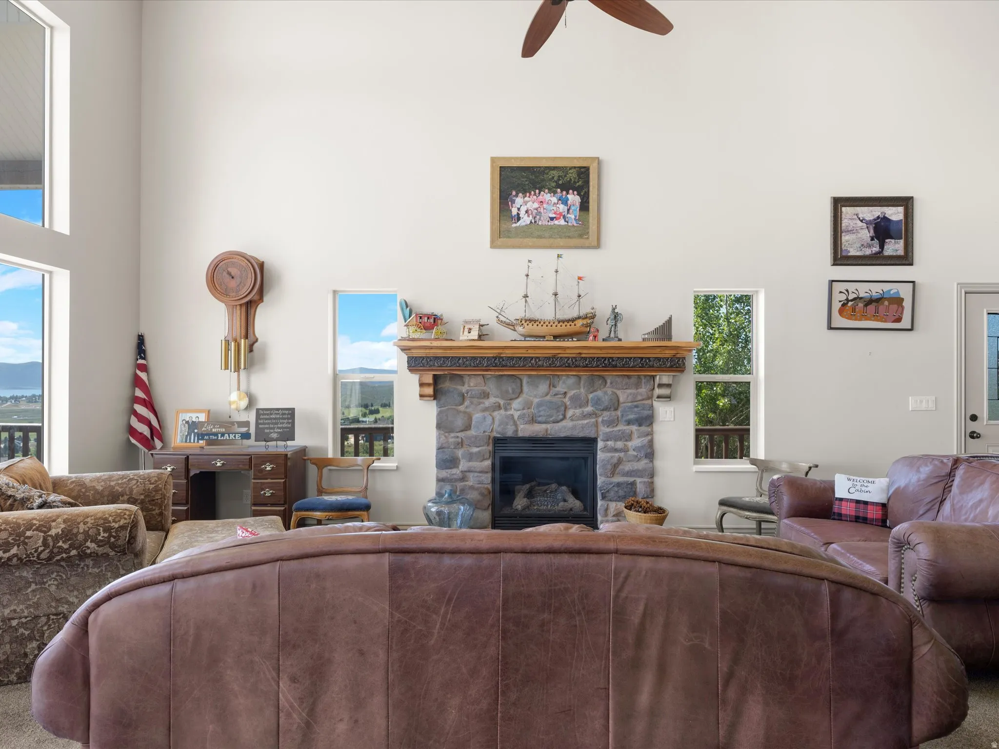 Vaulted ceilings enhance this living area featuring a stone fireplace with a carved wood mantel