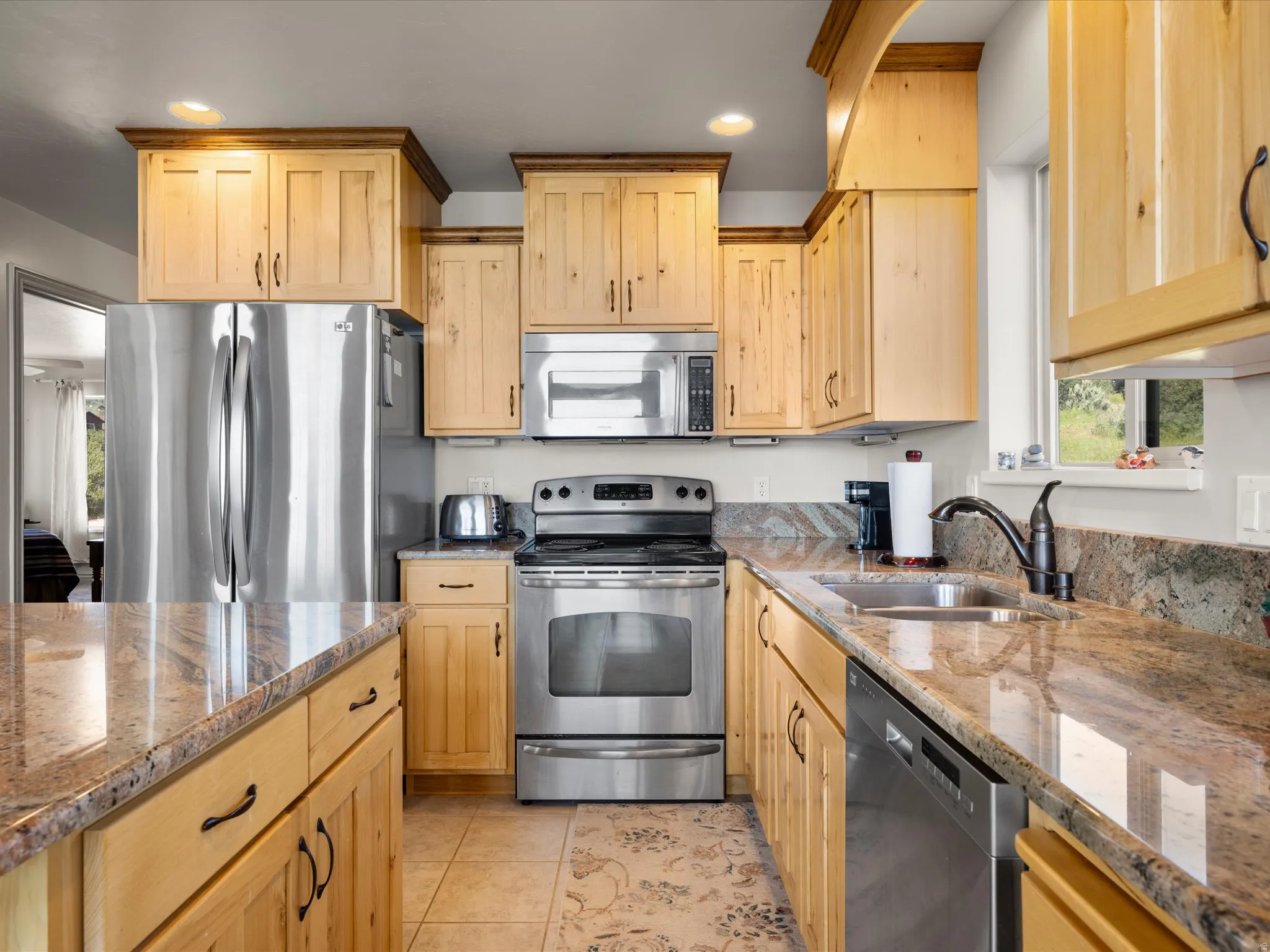 Kitchen featuring light wood cabinetry, stainless steel appliances, and stone countertops
