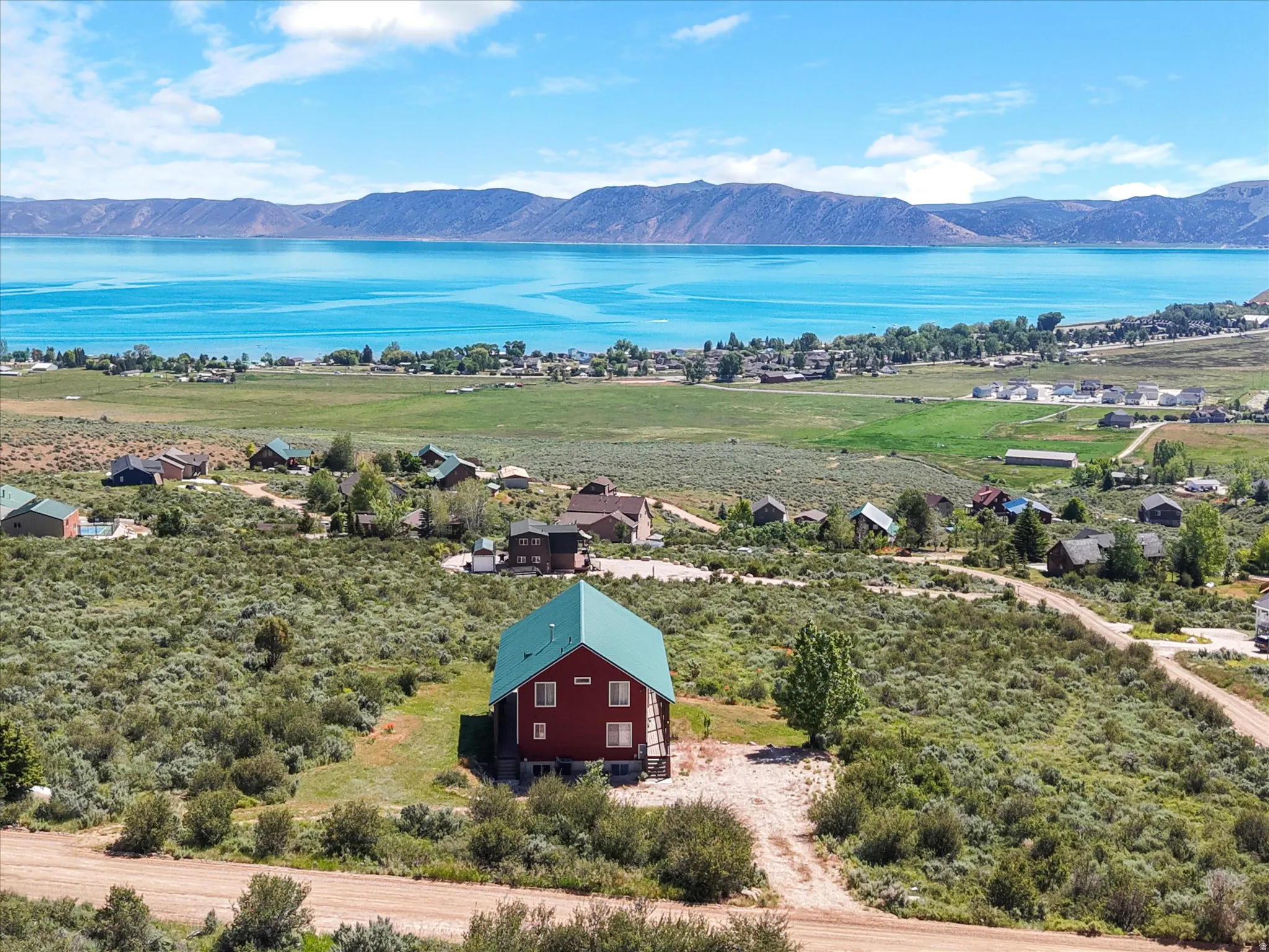 Exterior residence with a green metal roof, view of water and mountains