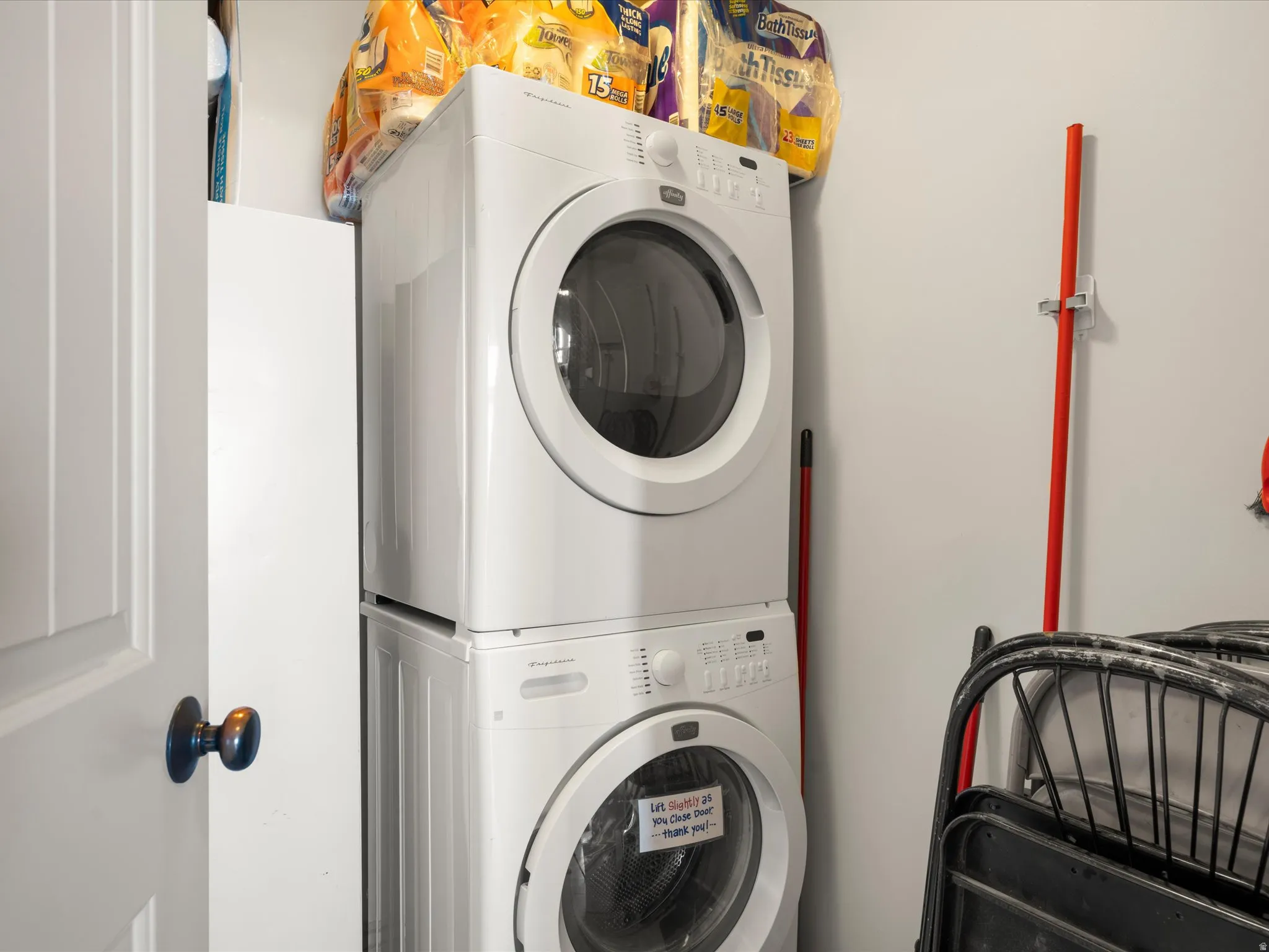 Dedicated laundry space featuring a white stacked washer and dryer, painted walls, and a white interior door with dark hardware