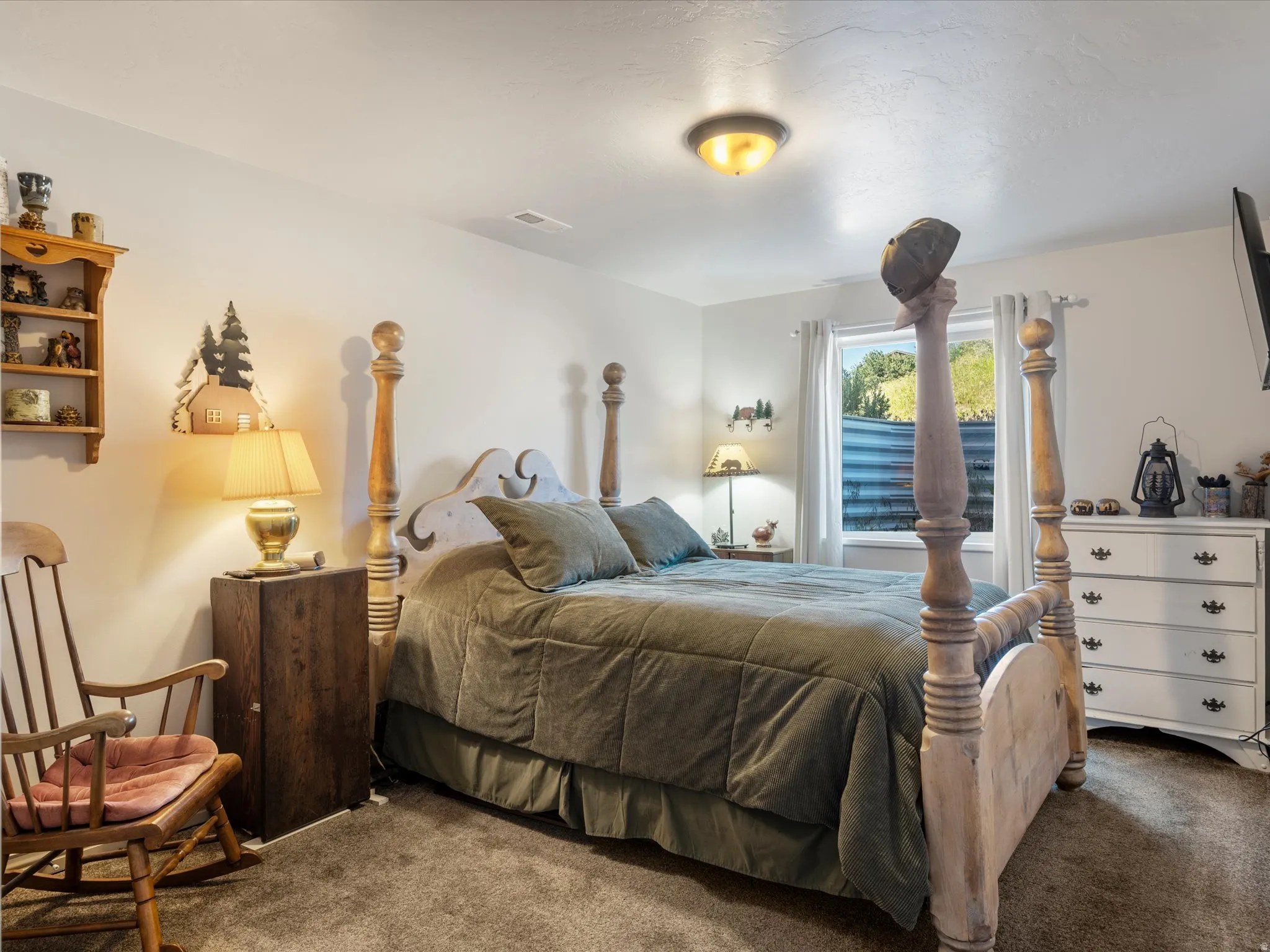Carpeted bedroom featuring a window, ceiling-mounted light fixture, and white walls