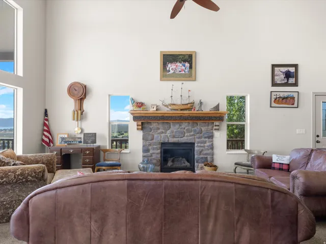 Vaulted ceilings enhance this living area featuring a stone fireplace with a carved wood mantel