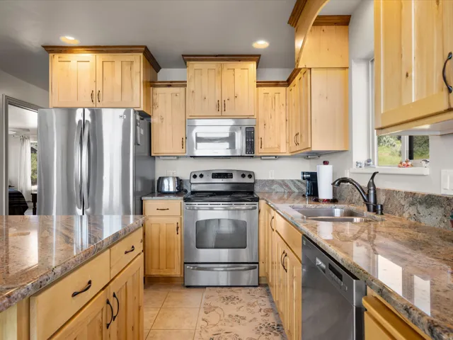 Kitchen featuring light wood cabinetry, stainless steel appliances, and stone countertops