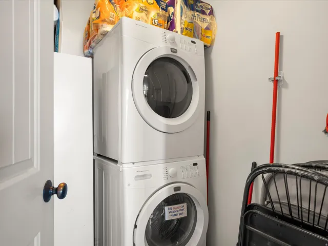 Dedicated laundry space featuring a white stacked washer and dryer, painted walls, and a white interior door with dark hardware