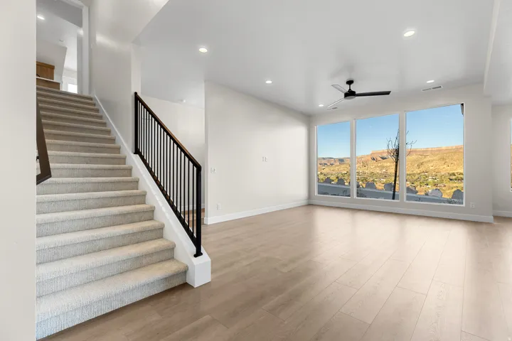 Spacious interior featuring wood-finish flooring, a contemporary ceiling fan, and recessed lighting